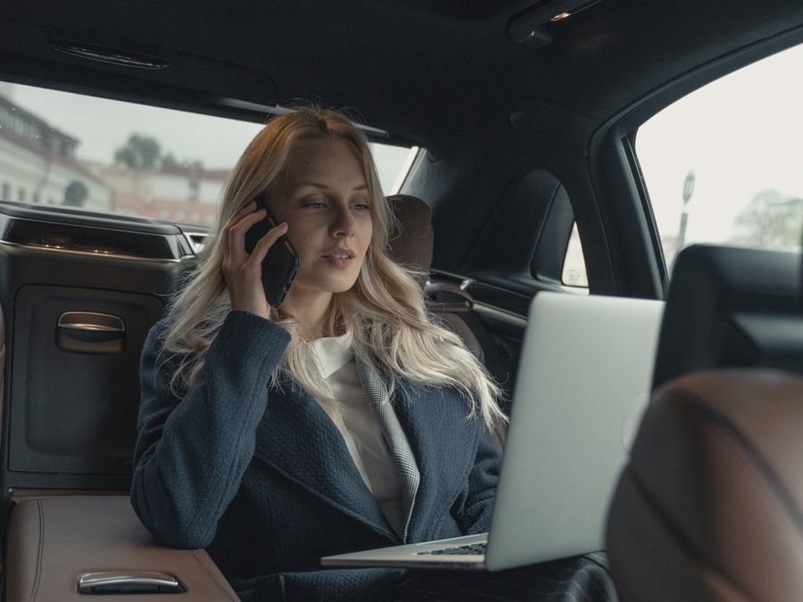 Passenger using the WhiBlu app on her phone in the back seat of a booked ride