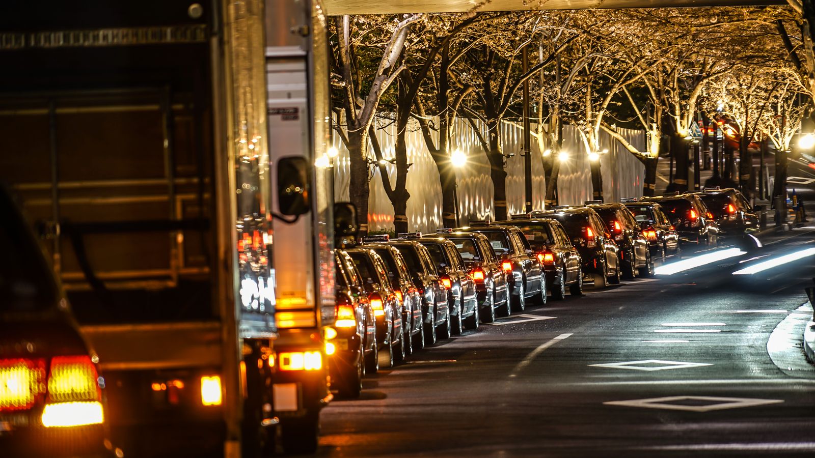 Street lined with vehicle lights as crowds leave an evening event