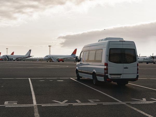 Six-seater van parked at an airport terminal ready for a group transfer